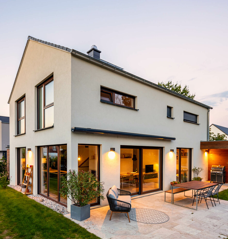 Modernes Massivhaus gebaut mit Roth mit Satteldach in abendlicher Stimmung beleuchtet