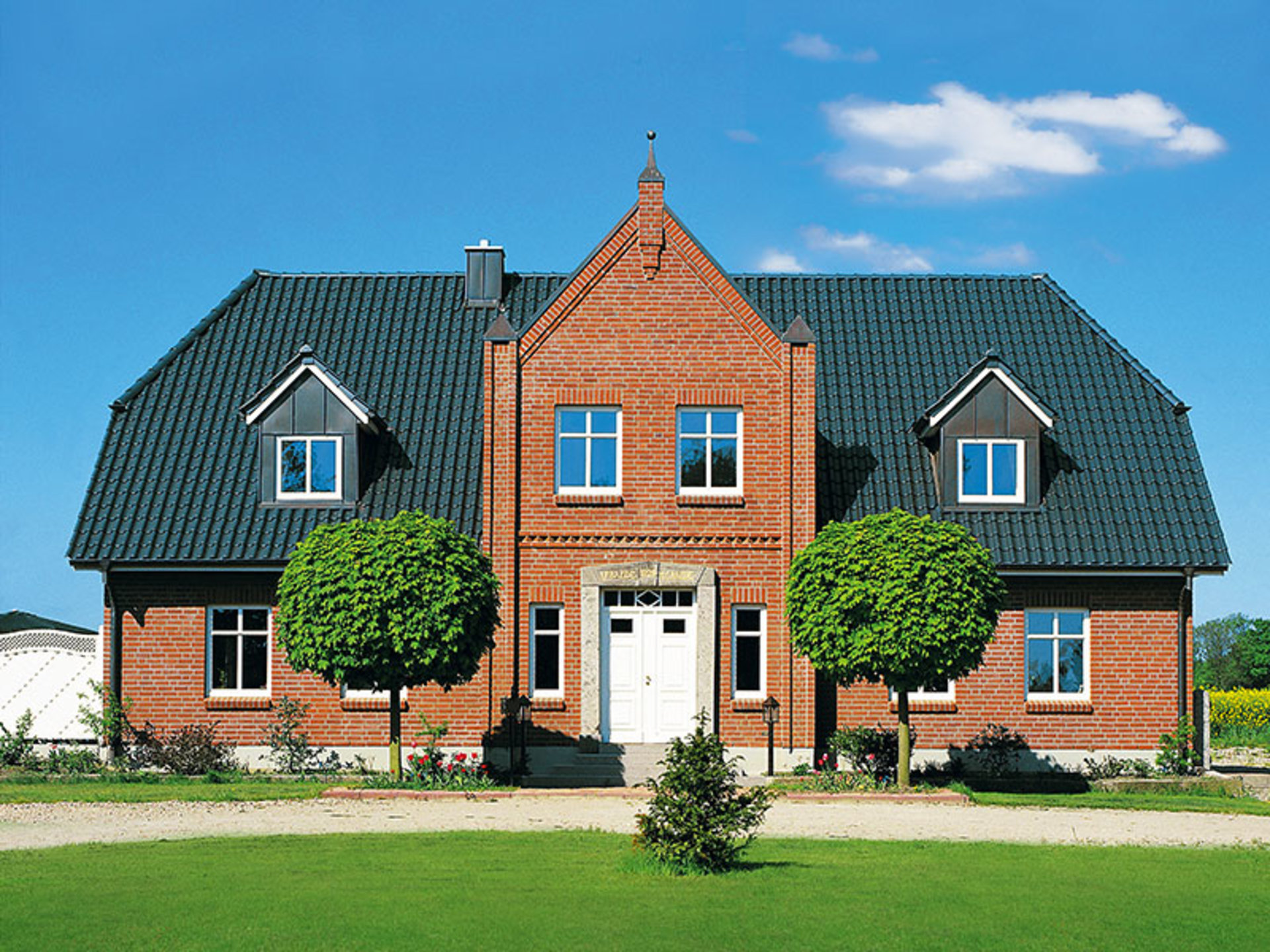 Haus Peters beeindruckt mit roter Backsteinfassade und großer Dachgaube (Foto: © BAUMEISTER-HAUS)